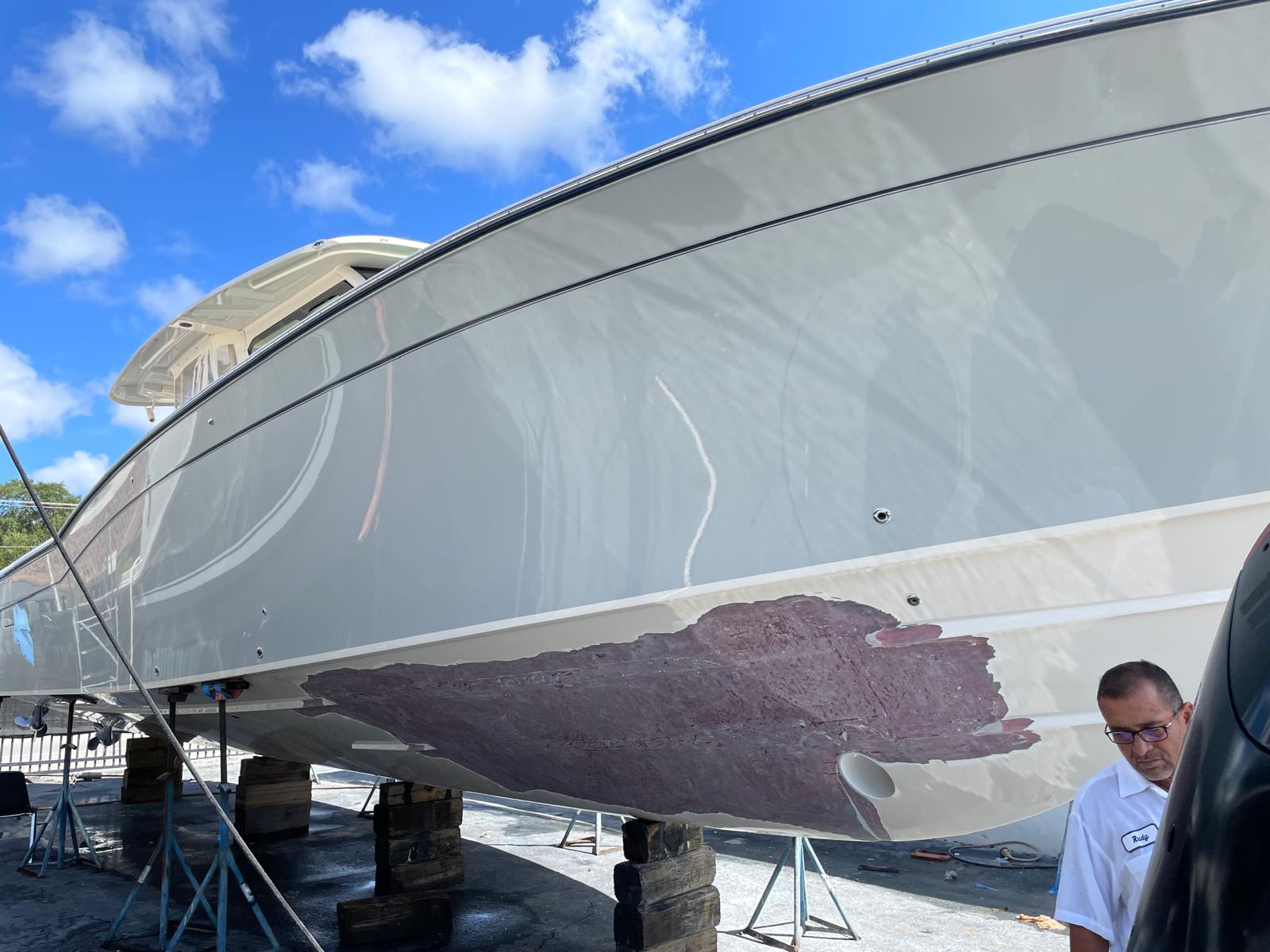 Gray center console hull with a large fiberglass repair area faired in red filler