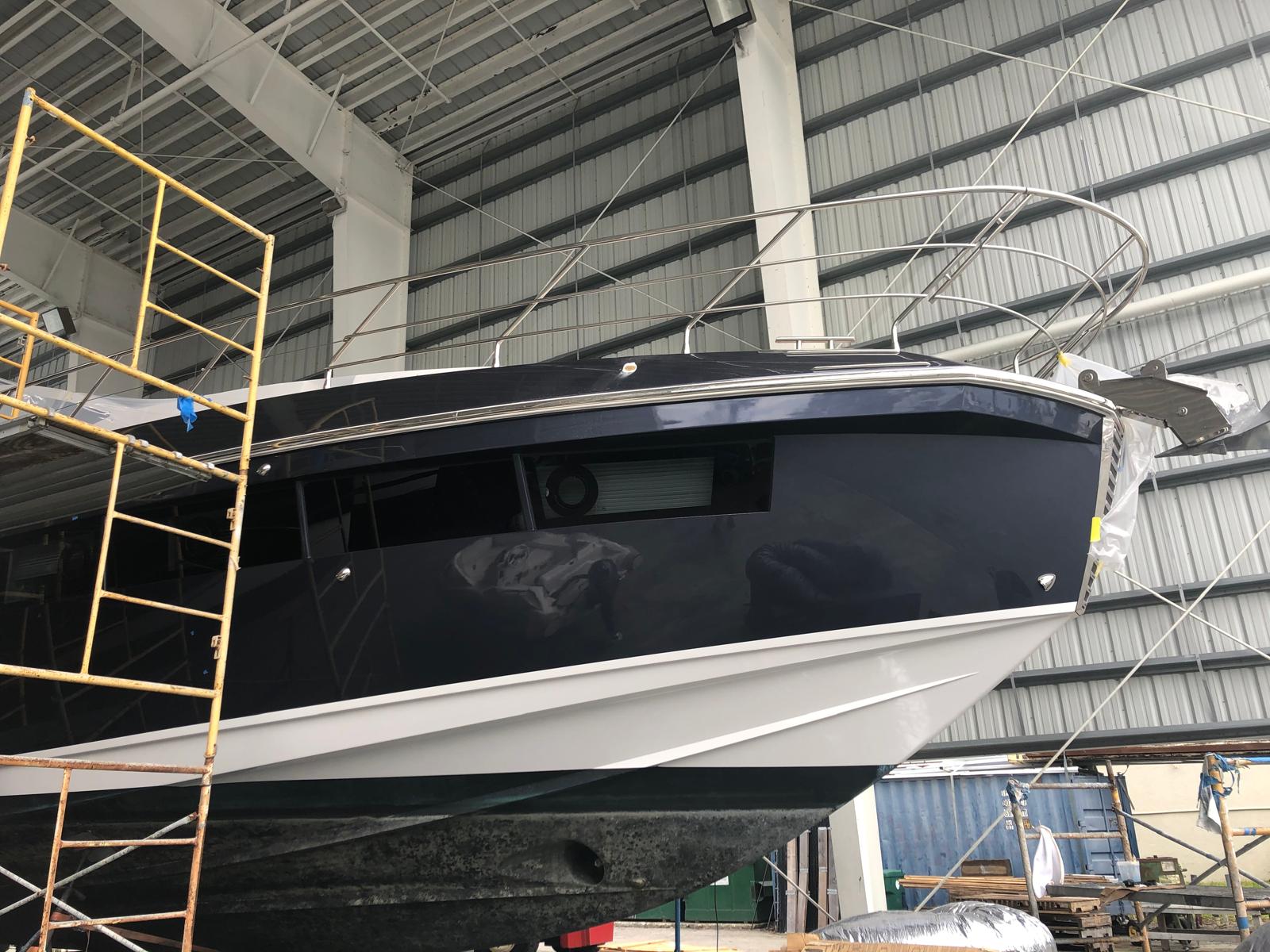 Freshly painted navy blue yacht hull with a high-gloss finish inside a South Florida boatyard