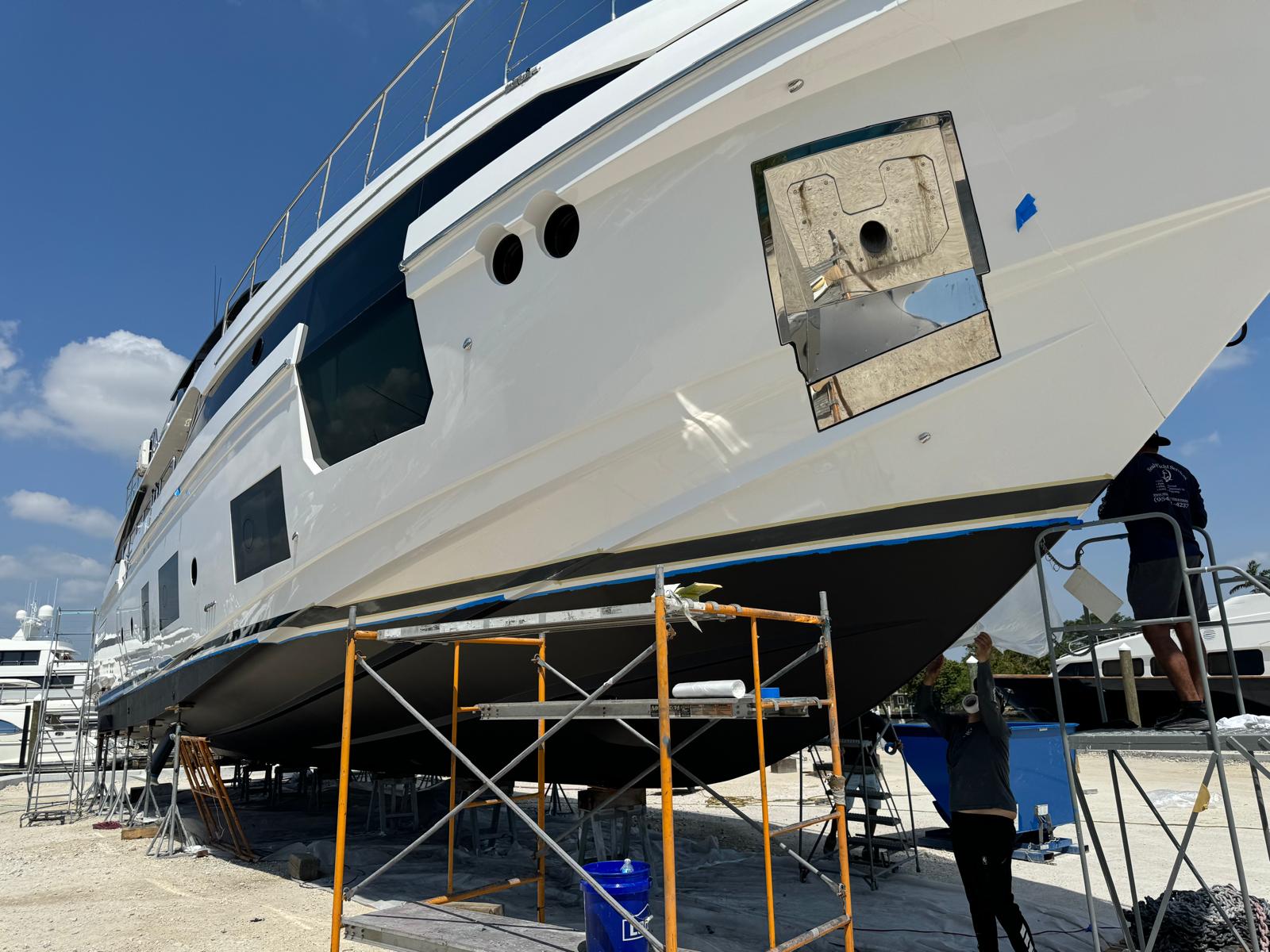 N&E crew removing masking from a freshly painted white superyacht hull
